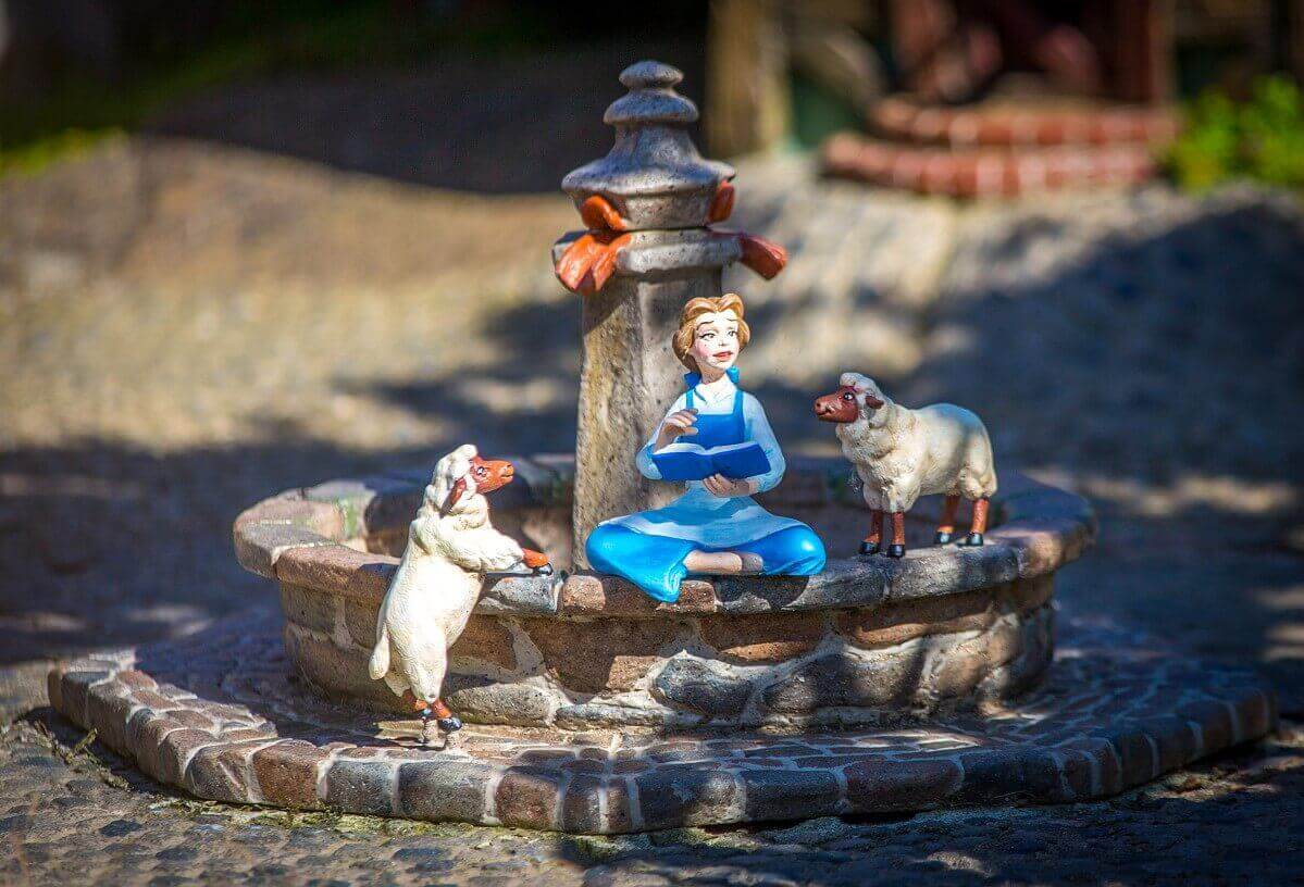 Belle at the village fountain near Le Pays des Contes de Fees a small figure of Belle sits at the village fountain in the Beauty and the Beast scene at Le Pays des Contes de Fees