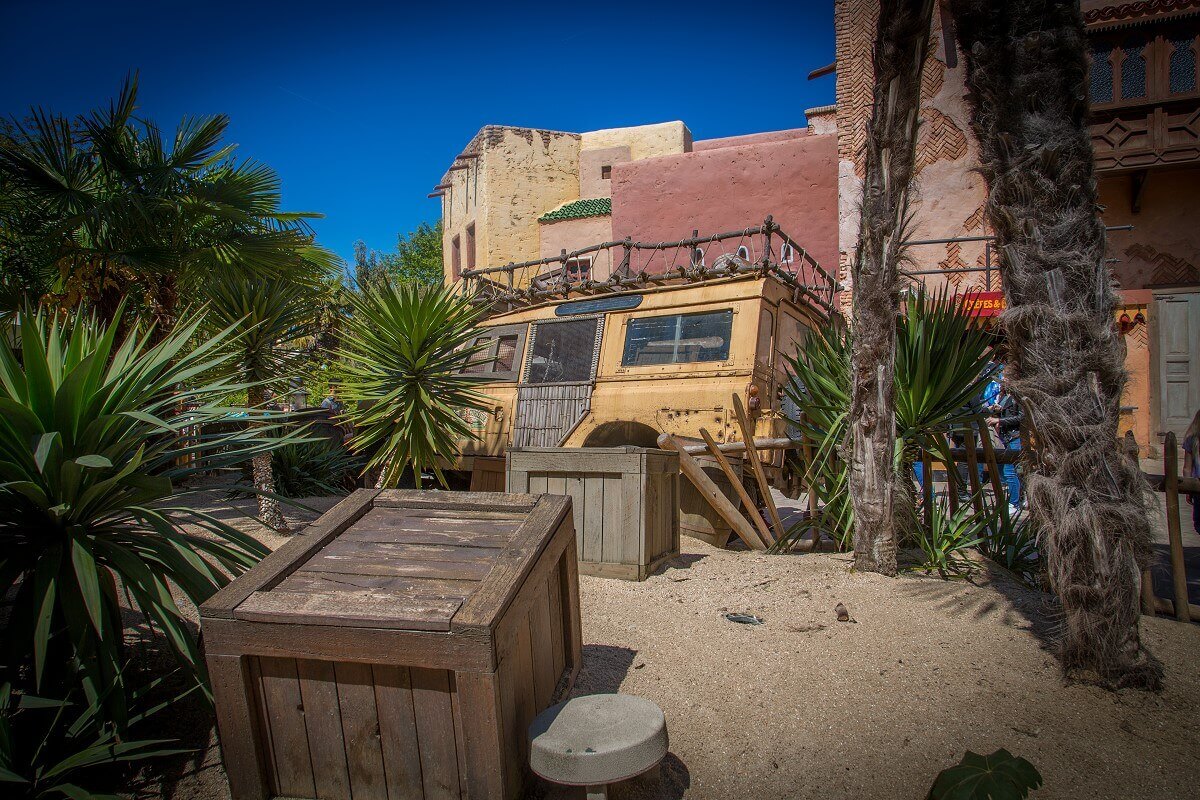 Wooden boxes and plants in front of a yellow truck View of some wooden boxes and palm trees on a sandy ground in front of a yellow truck in Adventureland