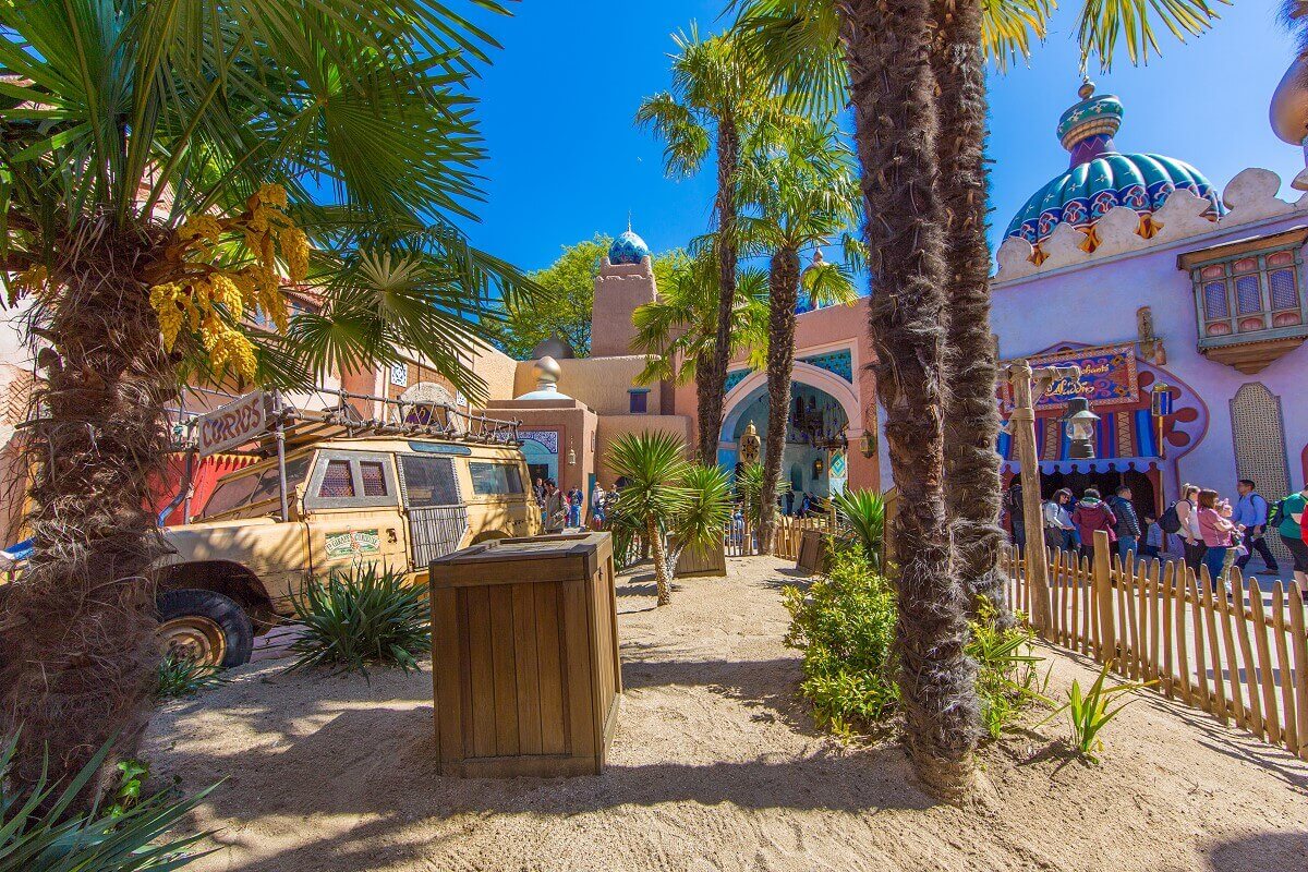 Decoration in Adventureland View of plants, a large wooden box and a yellow truck near the passage Enchants of the Aladdin