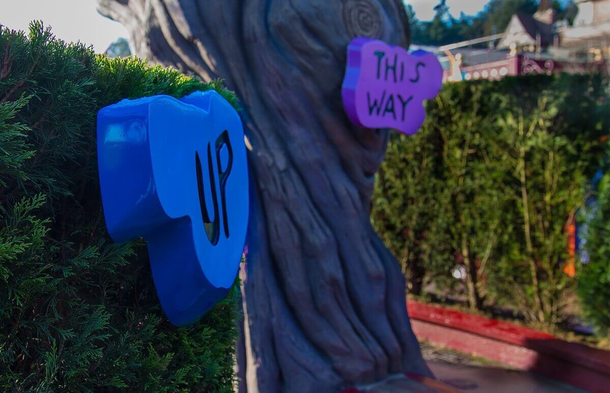 Guide two colourful signposts with the inscription Up and This Way point in different directions in the labyrinth