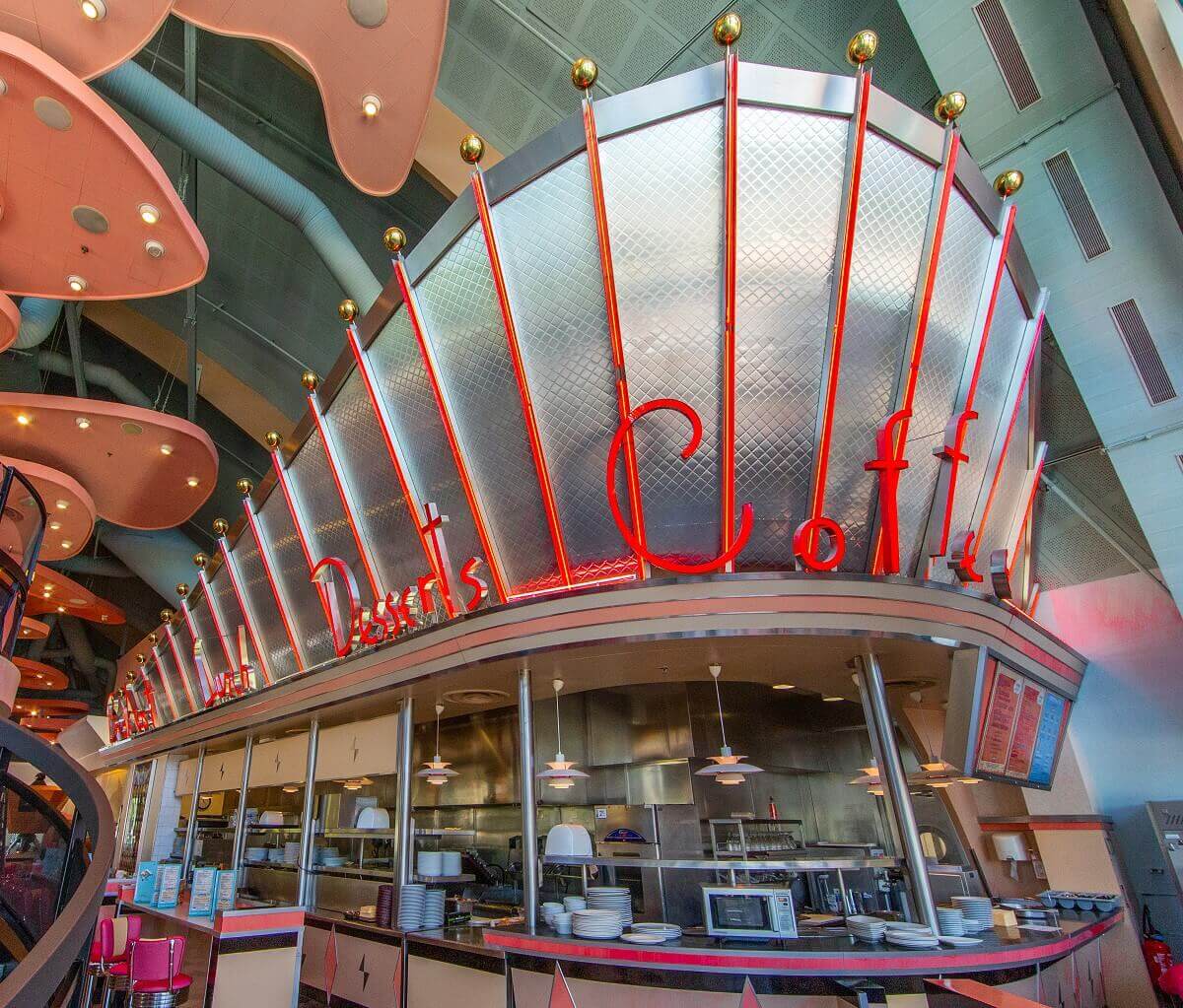 Open kitchen The open kitchen of Annette's Diner. The top is chrome and has red neon signs: Bugers, Salads, Desserts, Coffee