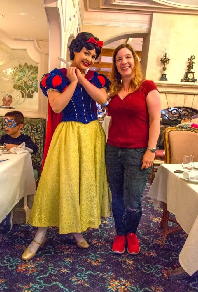 Meeting Snow White Snow White stands between two tables in the Auberge de Cendrillon next to Dörthe and smiles into the camera