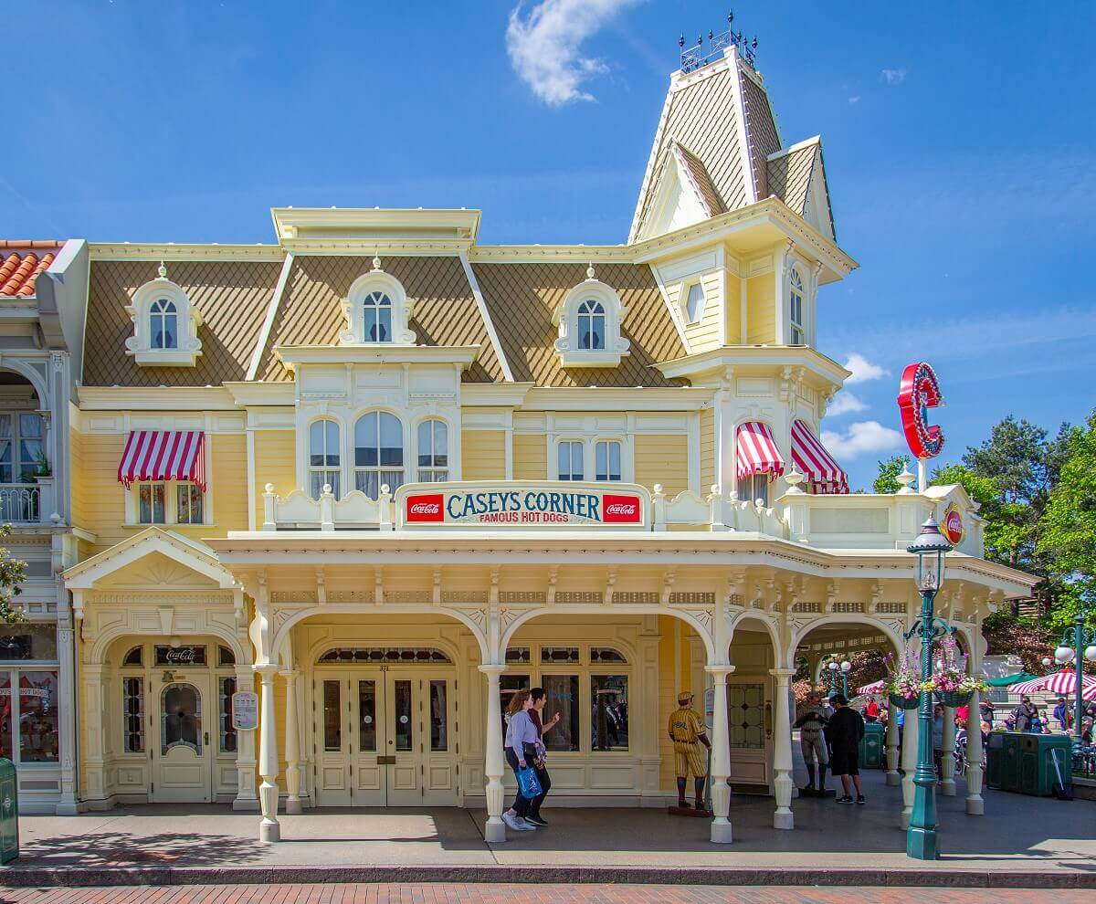 Casey's Corner from across the street. Casey's Corner from across the street, the building is cream in color and has a wooden arcade. There is a small turret at the top.