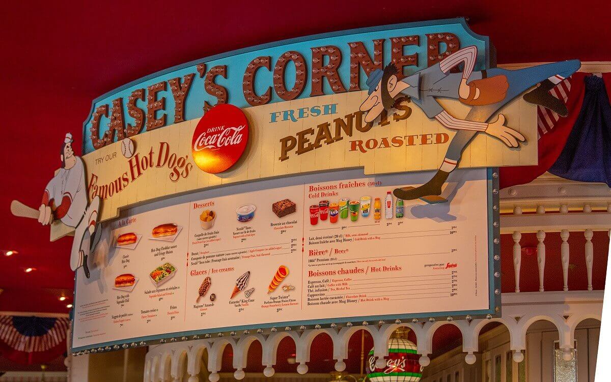 Menu The menu above the counter of Casey's Corner. For decoration there are two baseball players on the right and left side of the card, above the card the name of the restaurant and below the advertising slogans Try our Famous Hot Dogs and Fresh Peanuts Roasted