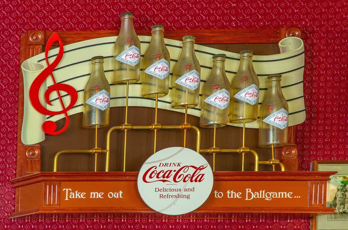 Coca Cola advertising sign Coca Cola advertising sign with old bottles displaying sheet music. Below text line of the song Take me out to the Ballgame