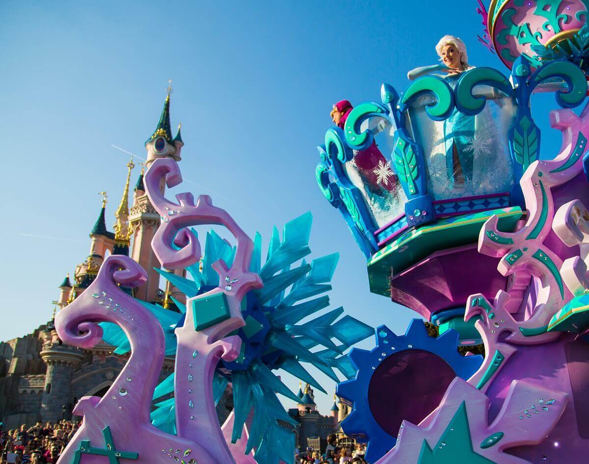 Sleigh with Anna and Elsa The parade float in the shape of a sleigh, on which Anna and Elsa are standing, drives in front of Sleeping Beauty Castle.