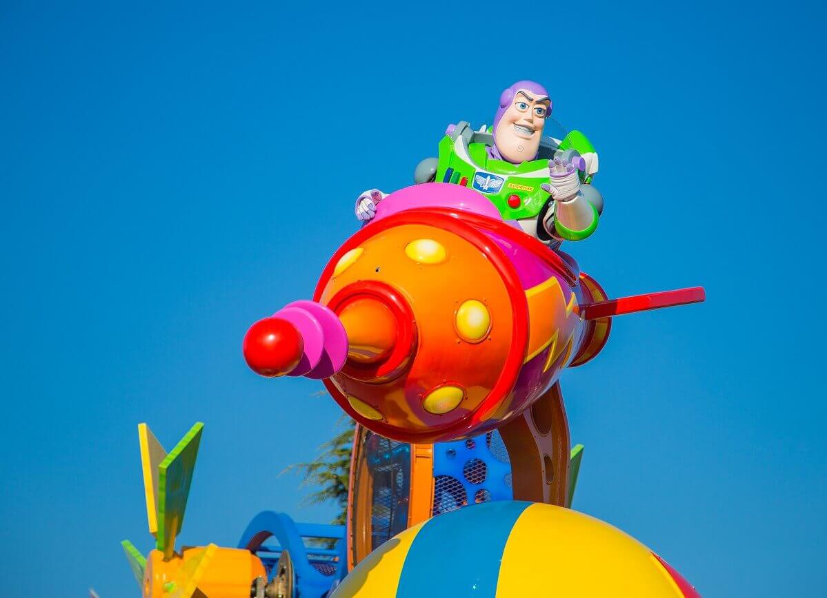 Buzz Lightyear in a rocket High atop a parade float floats a rocket in which Buzz Lightyear has taken a seat and waves