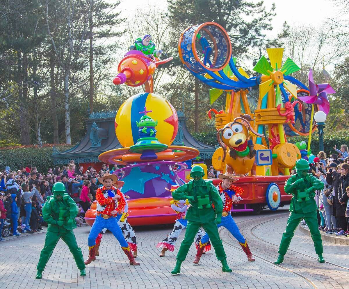 Toy Story Scene at Disney Stars on Parade Three green toy soldiers and some dancers dressed as Woody and Jessie lead the way to the giant Toy Story parade float just around the bend