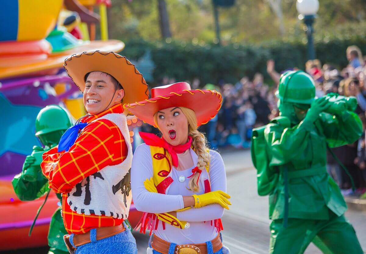 Parade dancers in the look of Woody & Jessie Two dancers stand back to back in the parade, wearing costumes with the look of Woody and Jessie