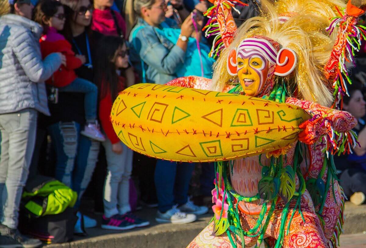 Colorfully dressed parade dancer A very colorfully dressed parade dancer with a wild blonde wig and vines around her neck. In her hands she holds an object that makes you think of a huge banana