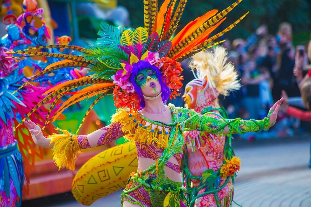Dancer in plant costume A dancer wears a brightly coloured costume with lianas that wrap around her body and a decoration of leaves, flowers and feathers.