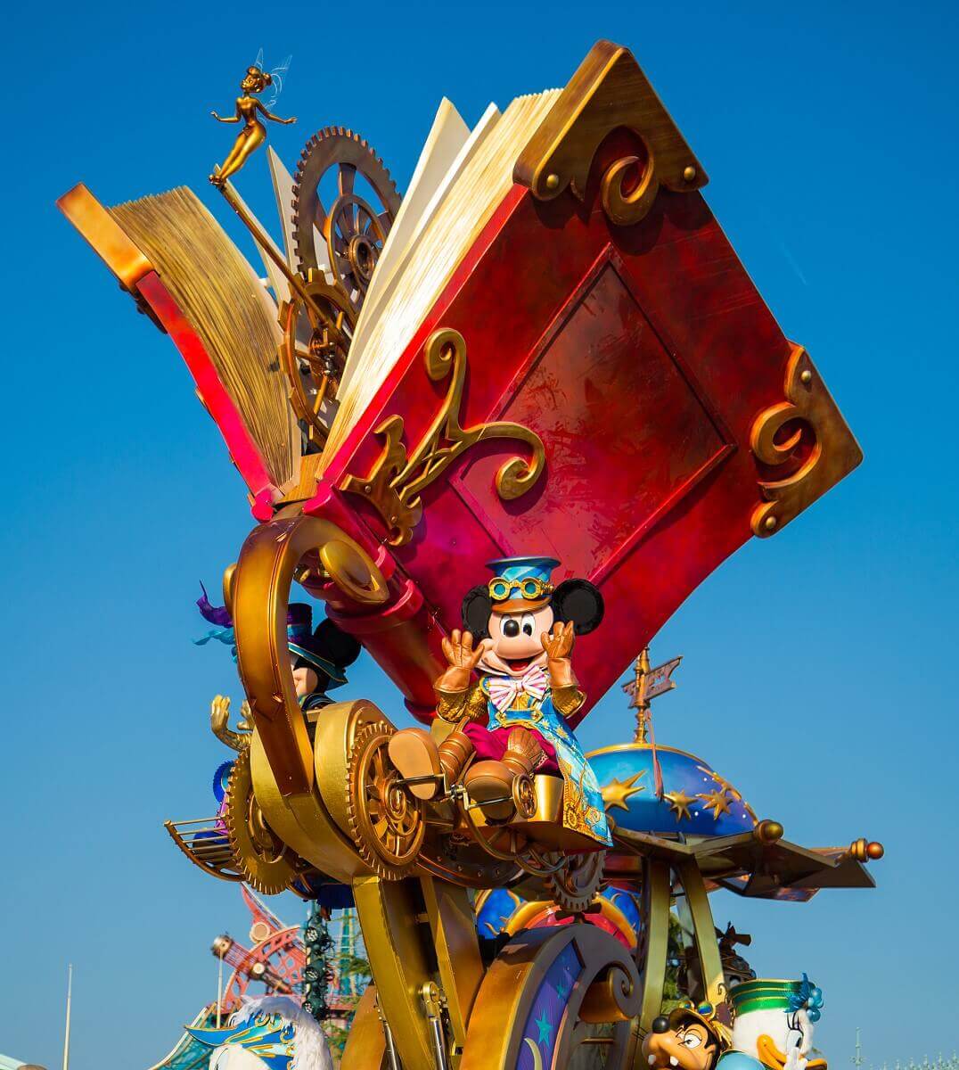 Mickey and the Storybook Mickey sits at a lofty height next to a giant storybook. Mickey wears a steampunk outfit and pedals the gears that make it turn