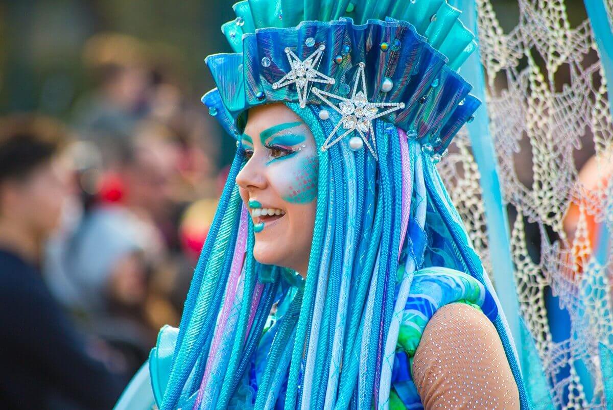 Dancer as water creature Side close-up of a parade dancer, in a water creature costume with blue-green hair with starfish stuck in it