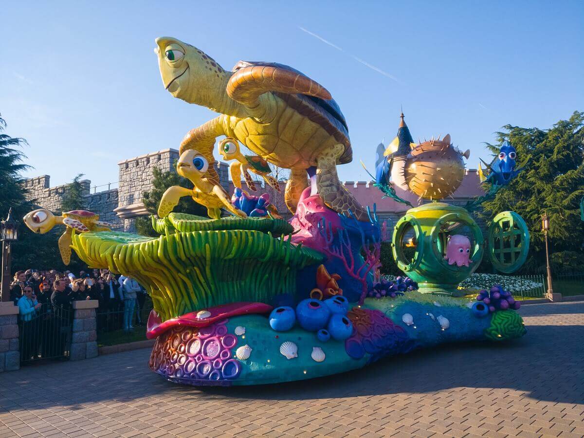 Finding Nemo parade float Crush, Racker and the Dudes swim over water plants, behind them a diving helmet is explored by Puff, Perle and Dory