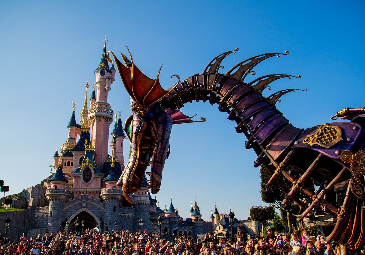 Dragon in front of the castle The big dragon from the parade has his head tilted forward while he is passing Sleeping Beauty's Castle