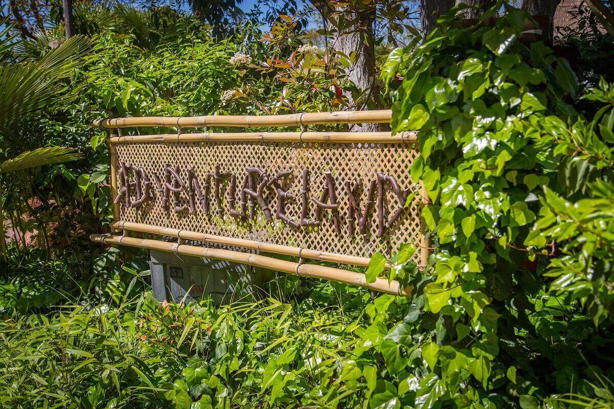 Sign Sign with the inscription Adventureland in front of a bed of various plants