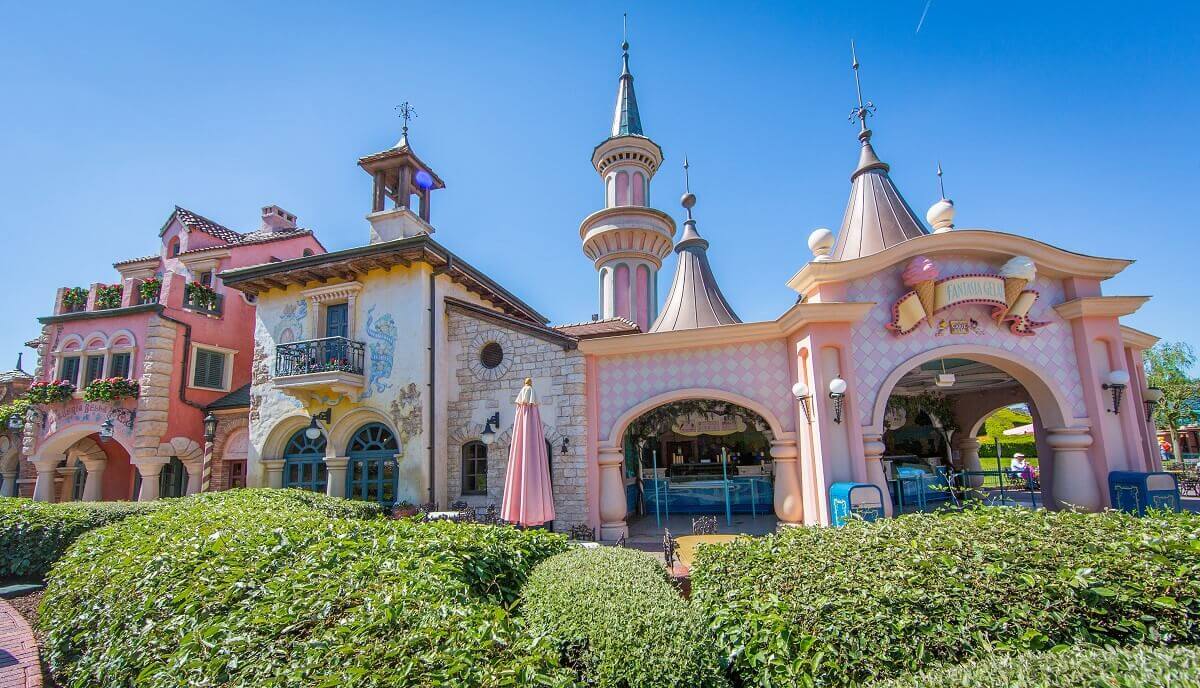 Building in Fantasyland behind a hedge you can see the buildings of the Pizzeria Bella Notte and the ice cream parlour Fantasia Gelati in Fantasyland