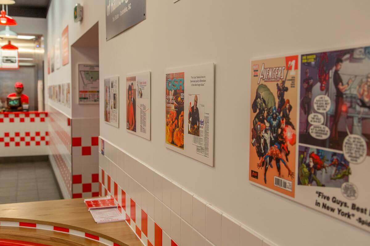 View over a wall with newspaper reports about Five Guys Looking over a wall of newspaper stories about Five Guys, including a Marvel Avengers comic featuring Five Guys.