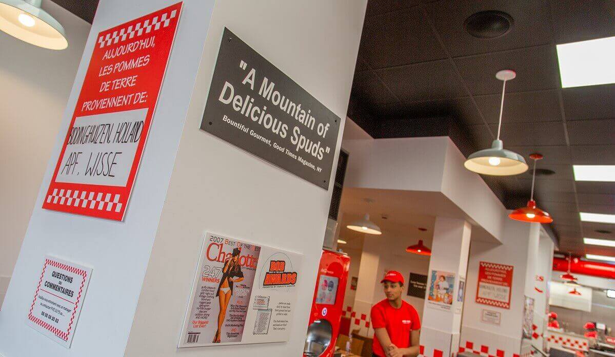 Indication of the origin of the ingredients on a sign and newspaper clippings about Five Guys. Indication of the origin of the ingredients on a sign and newspaper clippings about Five Guys.