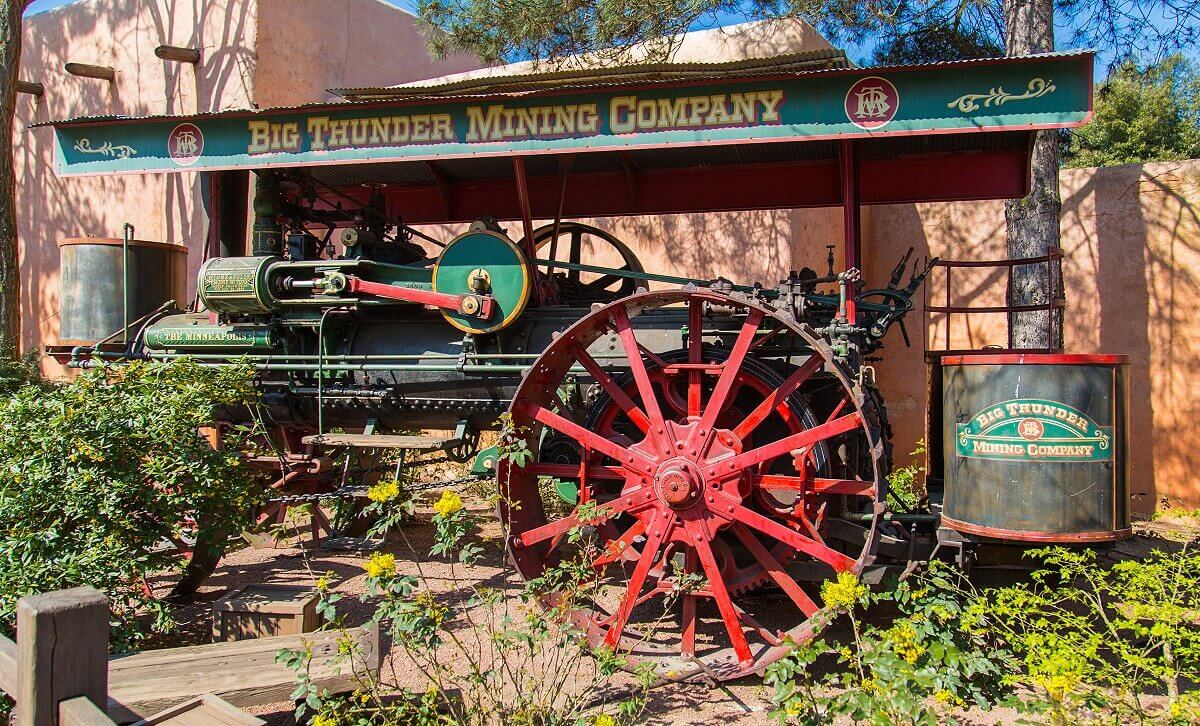 Machine of the Big Thunder Mining Company A large machine of the Big Thunder Mining Company stands on a small green area near the fast food restaurant Fuente del Oro