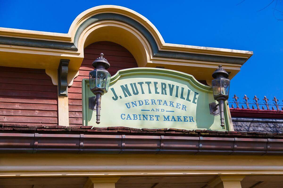 Advertising for the undertaker A green sign with two lanterns advertises the services of undertaker and coffin maker J. Nutterville in Frontierland