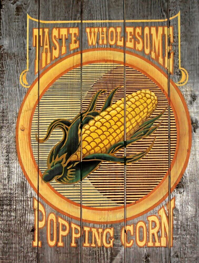 Advertising sign in Frontierland An image of a corncob and the words Taste Wholesome Popping Corn are visible on a wooden paneling