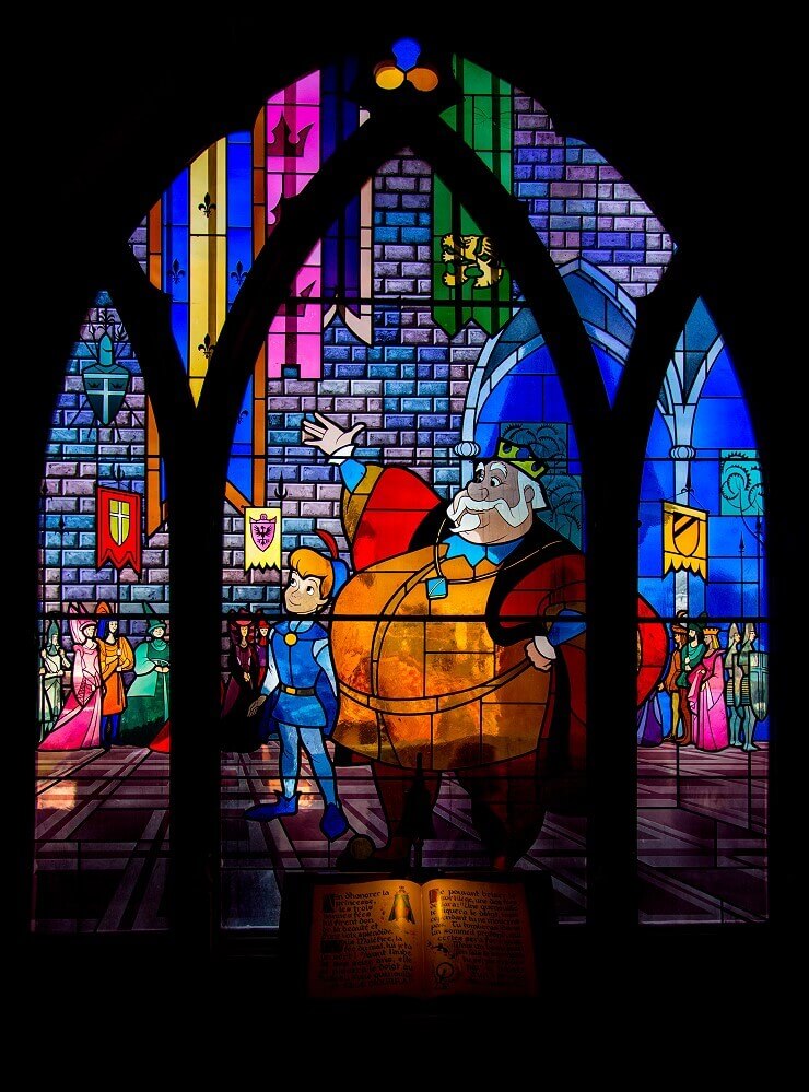 Stained glass window with Sleeping Beauty scene A stained glass window showing a fat king, in front of it an open storybook
