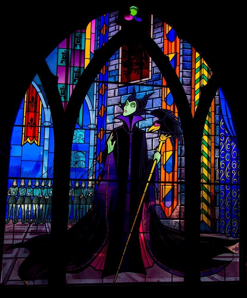 Stained glass window with malefic A stained glass window shows Malefiz in her flowing cloak, on a staff she holds in her hand sits a raven