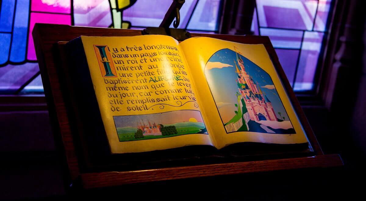 Desk with storybook On a wooden desk lies an open storybook with a picture of Sleeping Beauty Castle