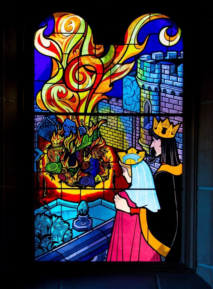 Stained glass window to Sleeping Beauty A stained glass window shows the scene from Sleeping Beauty where spinning wheels are burned in the castle courtyard