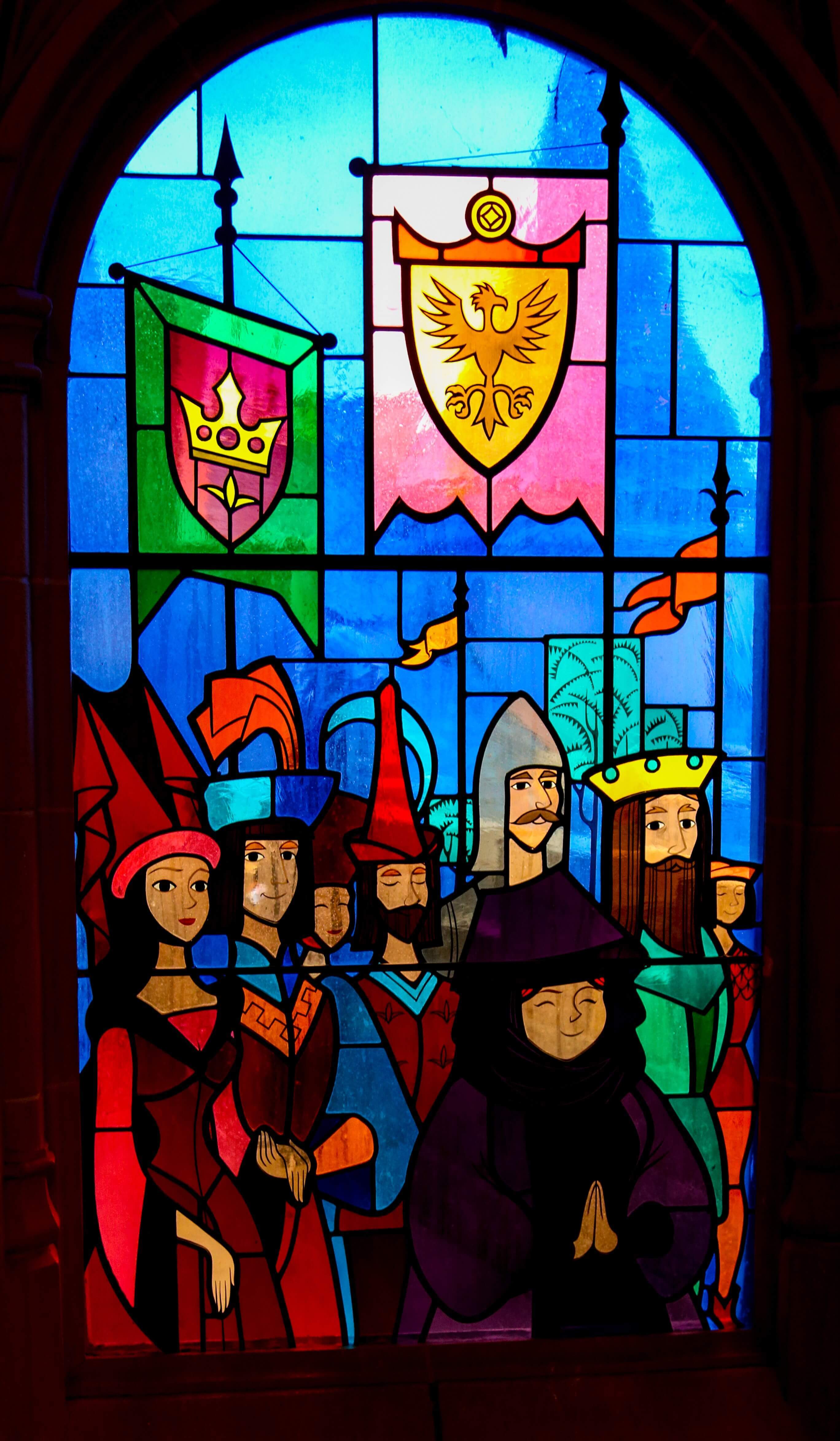 Stained glass window knights and ladies of the court A stained glass window shows knights and ladies of the court with their banners and flags