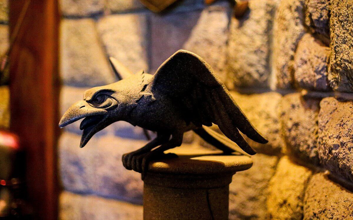 Stone raven A stone raven sits with spread wings on a pedestal