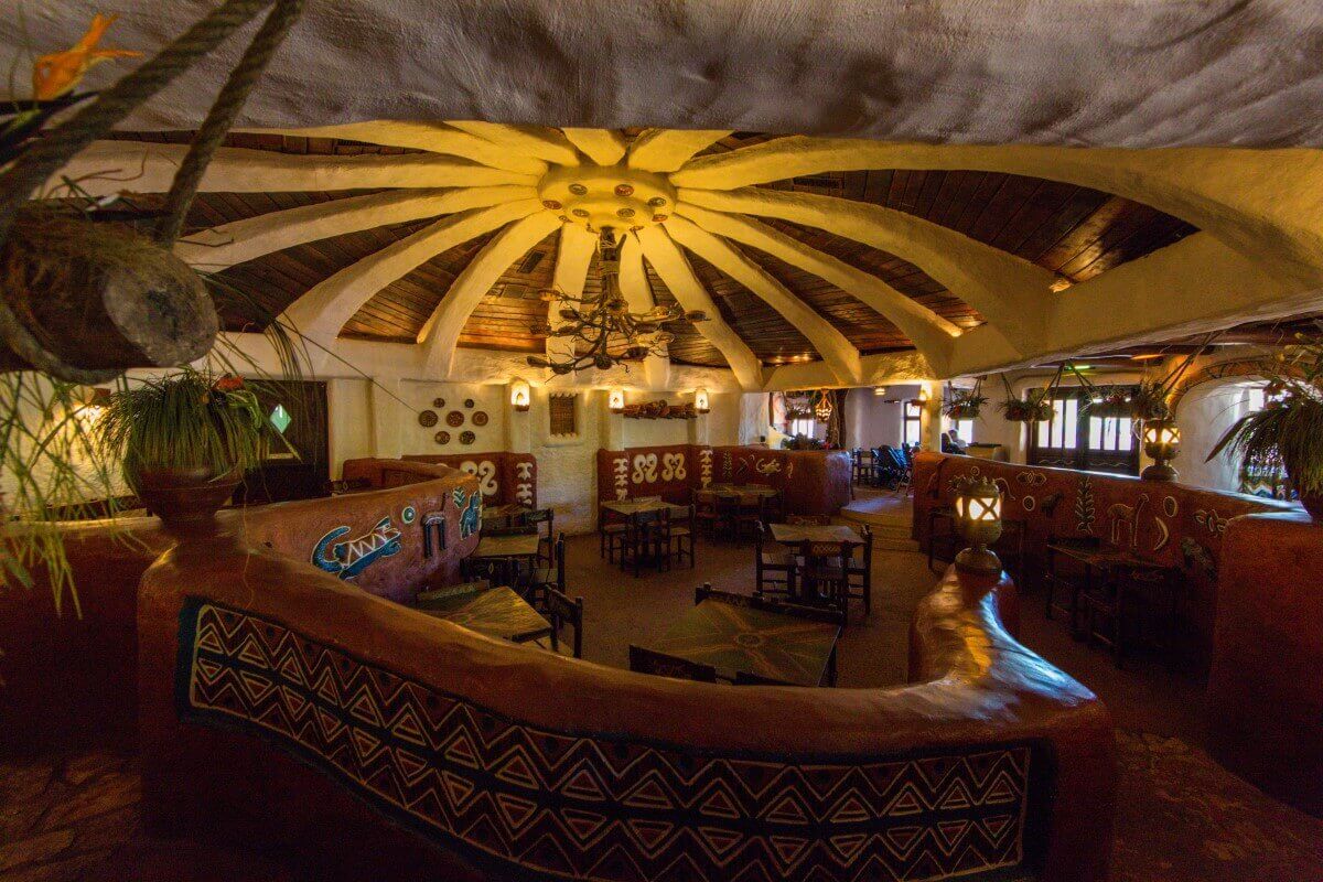 African design of the interior View of a mid-height wall with African décor and several tables in the Hakuna Matata restaurant.