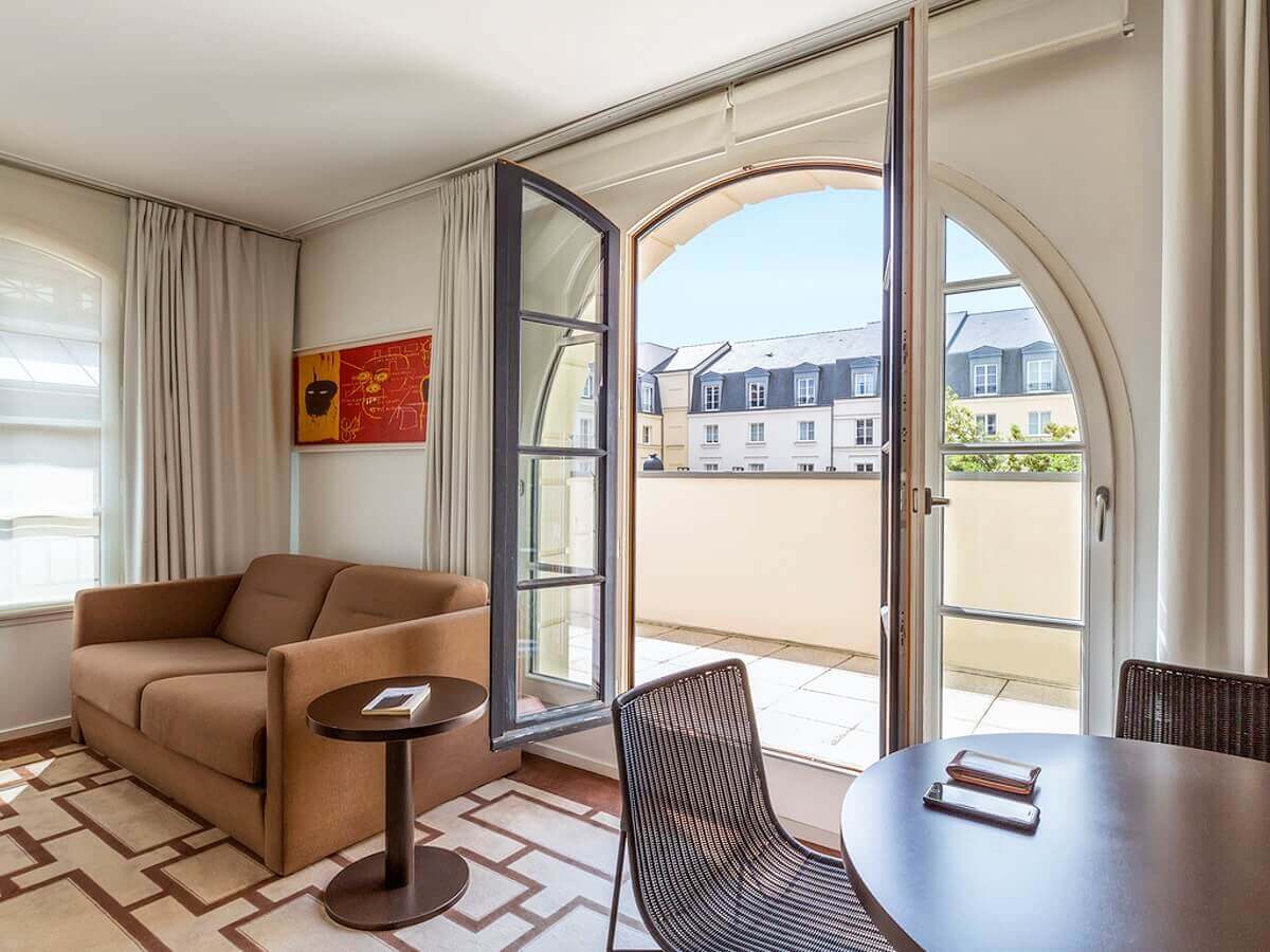 View from the hotel room Hotel room with large window and balcony, in the room there is a sofa and a table with chairs