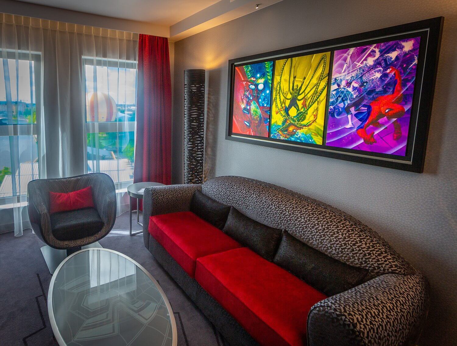 Spider-Man Suite living area A red / black sofa, an armchair with a table in the living area of the suite hangs a large picture of Spider-Man on the wall