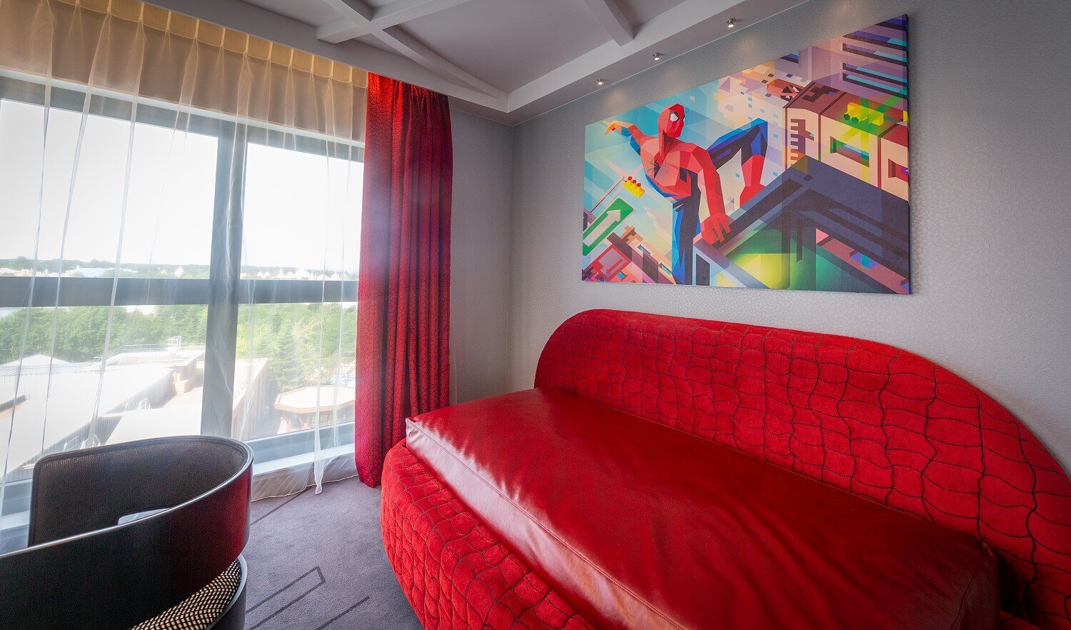 Spider-Man Suite living area A picture of Spider-Man hangs over a red sofa