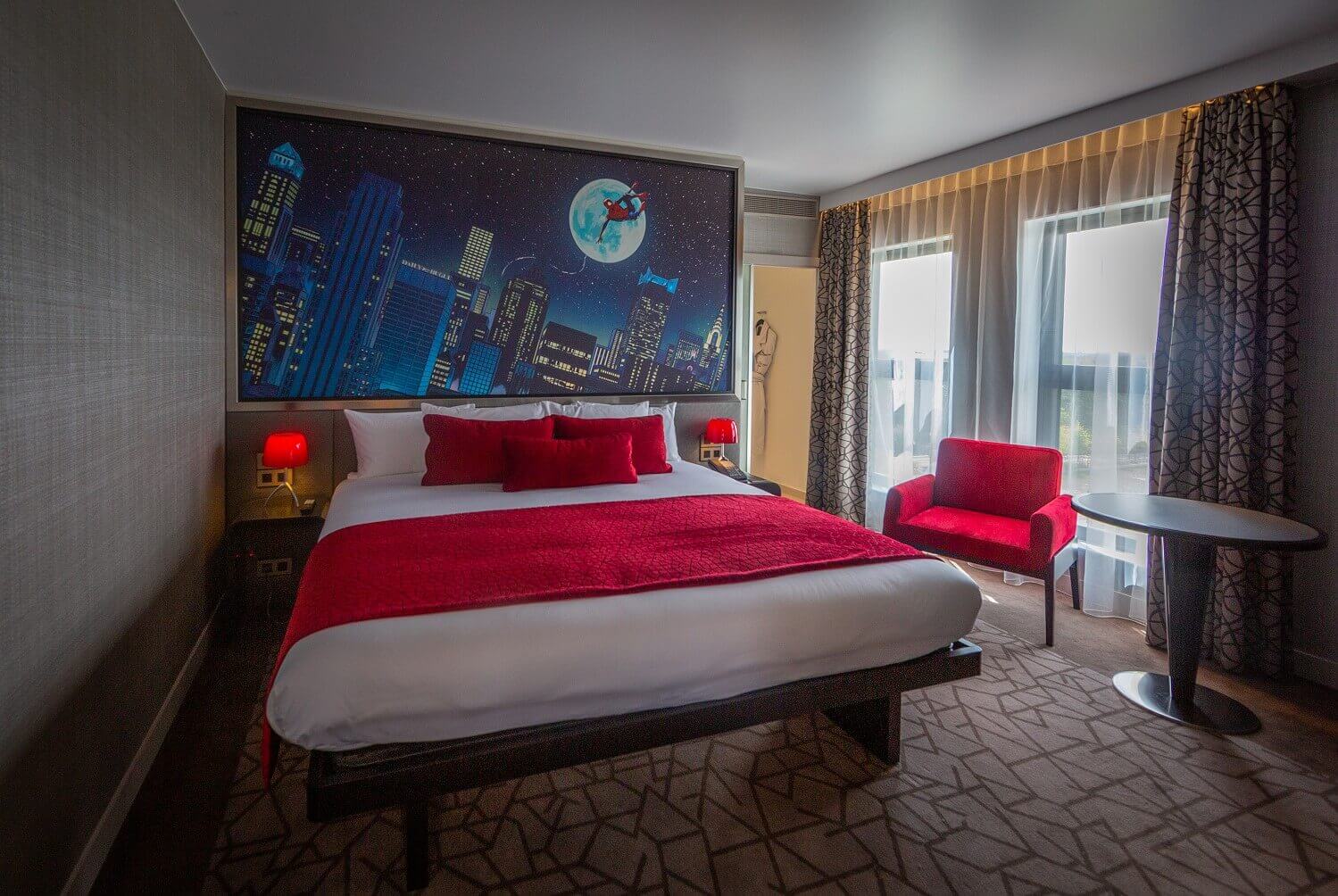 Spider-Man Suite sleeping area Above the bed hangs a picture of Spider-Man over the rooftops of New York by night