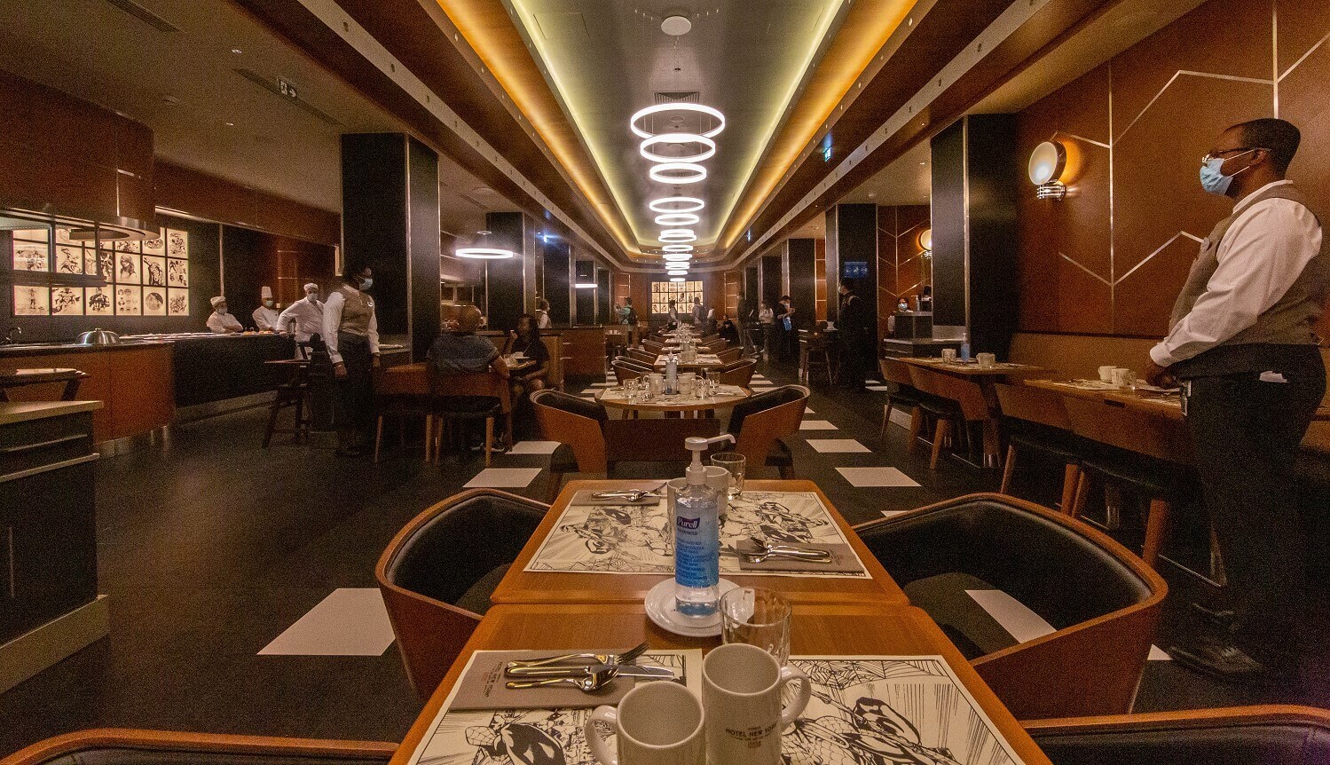 Tables in the downtown restaurant the tables in the downtown restaurants with superhero placemats, in the middle of the table there is a disinfectant dispenser