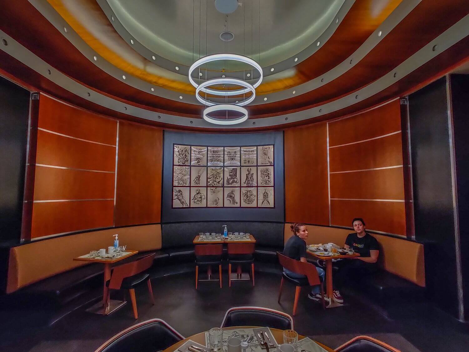 Pictures and lamps in the downtown restaurant The walls of the restaurant are adorned with Marvel works of art, and the ceiling is hung with a modern lamp made of three rings