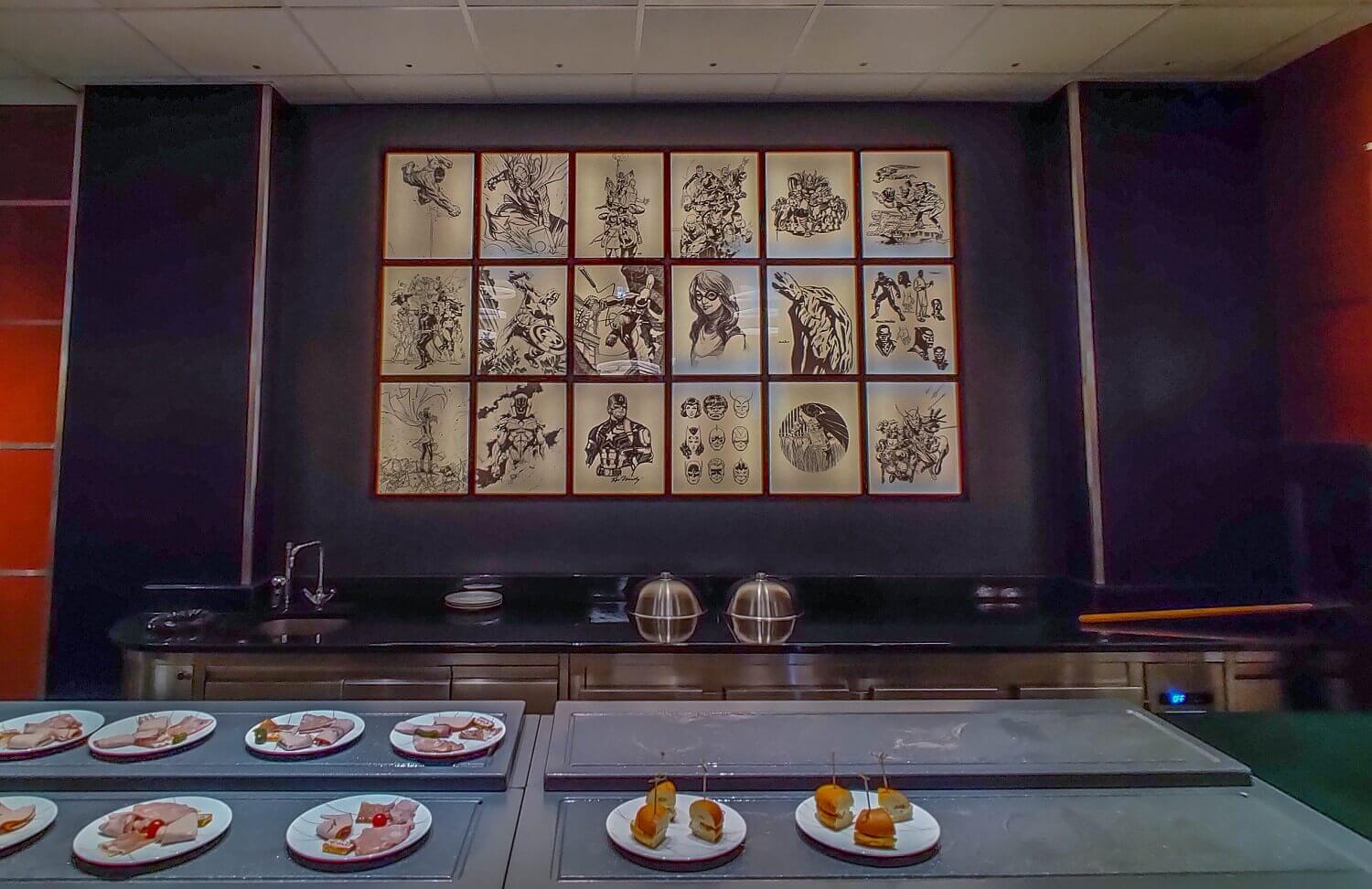 Downtown restaurant buffet Buffet with several sausage plates and appetizers. Behind it a mural with Marvel heroes.