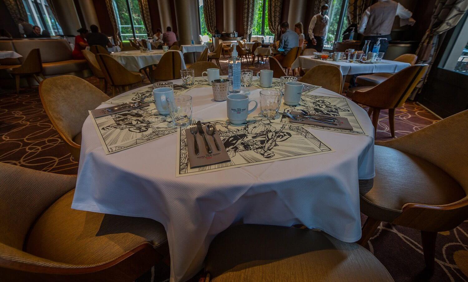 Manhattan Restaurant Close up of a table set for the breakfast buffet. The placemats have different Marvel motifs.