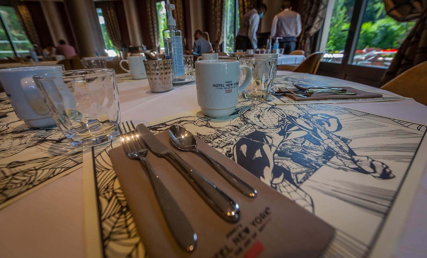 Manhattan Restaurant Close up of a table set for the breakfast buffet. The placemats have different Marvel motifs.