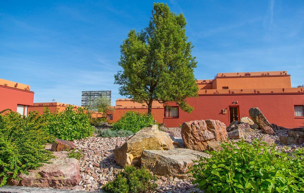 Santa Fe Hotel Building A small gravel garden with shrubs, a tree and boulders.