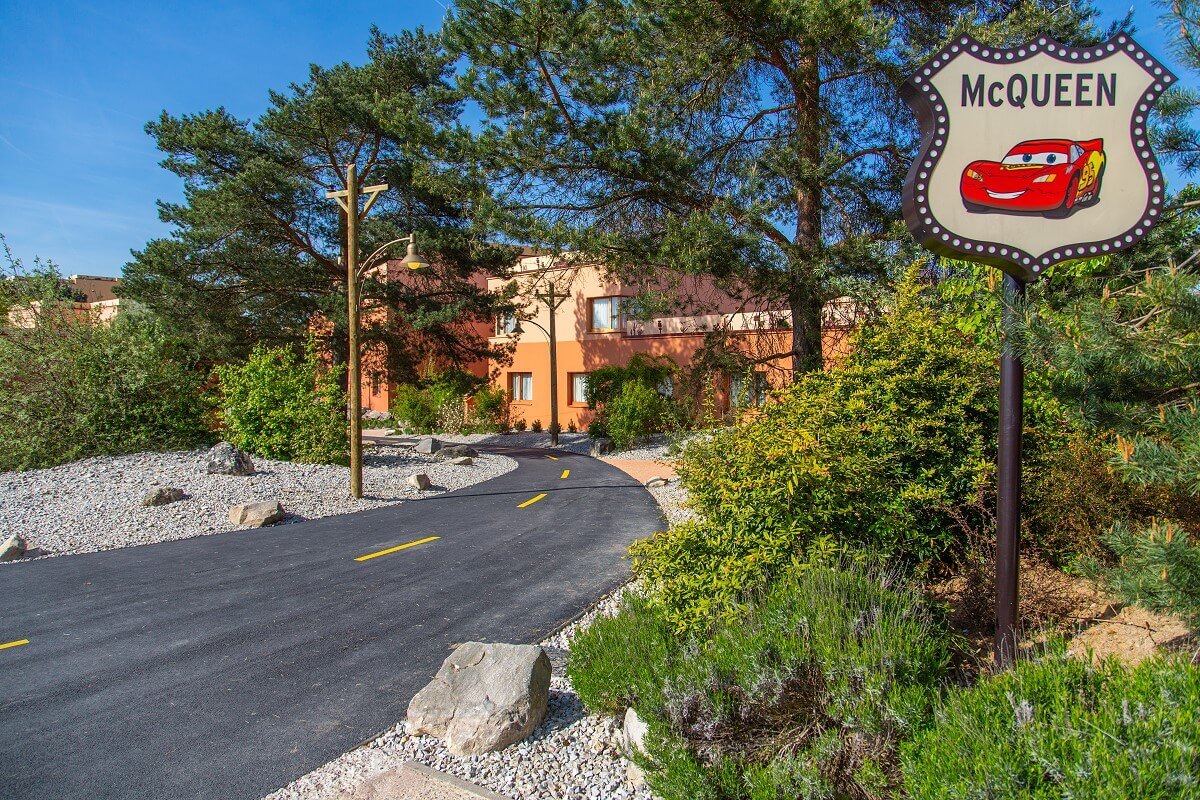 Santa Fe Hotel Building with Route 66 Next to Route 66 is a sign with Lightning McQueen on it. In the background you can see a hotel building.