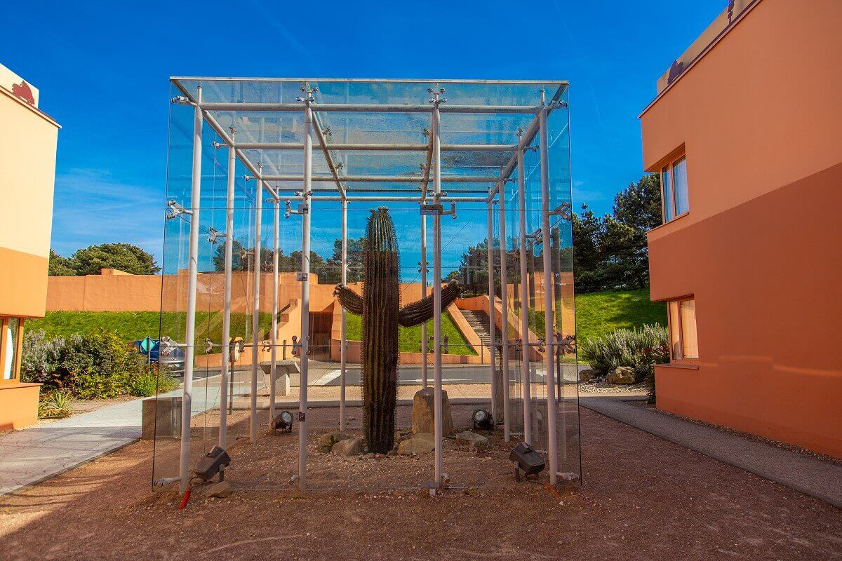 Cactus on the hotel grounds A large cactus stands in a glass pavilion between two hotel buildings.