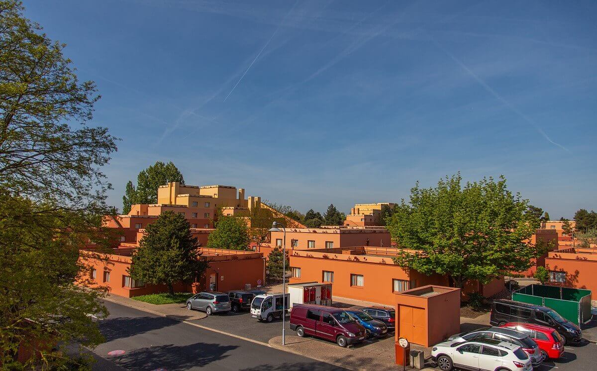 Santa Fe Hotel Building An orange hotel building of the Santa Fe, in front of it are parked cars and some trees can be seen