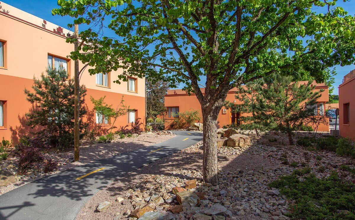 Santa Fe Hotel Building with Route 66 Next to Route 66 you can see trees, rocks and a hotel building.
