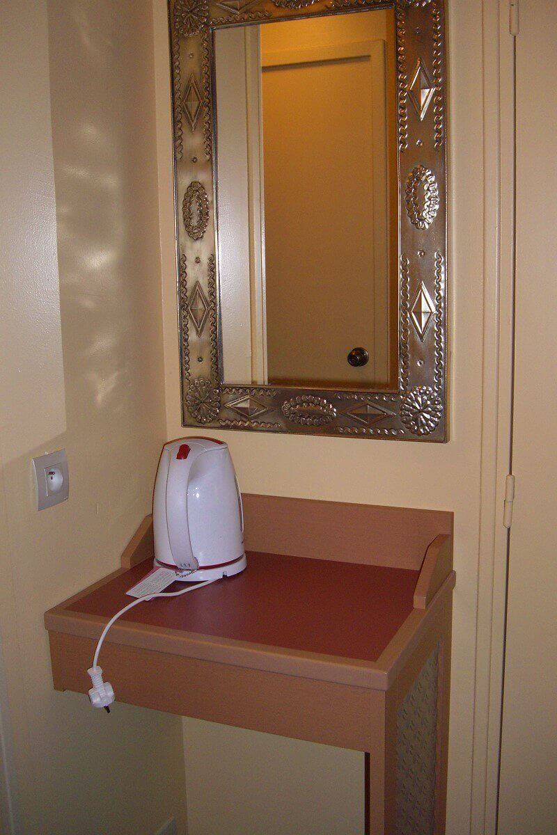Kettle in the hotel room A kettle stands on a shelf in the hotel room, a mirror hangs on the wall above it