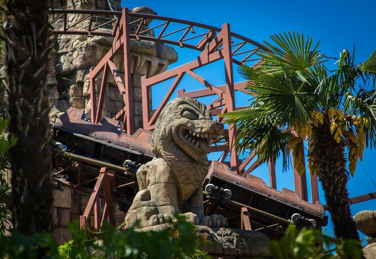 Parts of the roller coaster View of a stone figure, plants and some tracks of the roller coaster Indiana Jones