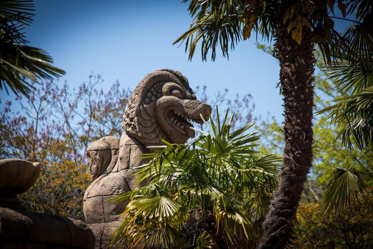 Stone figure through tropical plants a stone figure of a lion-like animal can be seen
